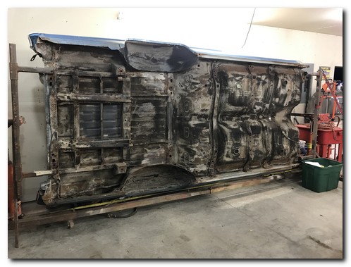 Body on rotisserie against wall
